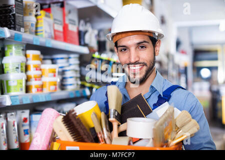 Happy  workman holding basket with picked tools in paint store Stock Photo