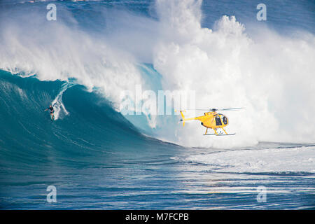 A helicopter filming a tow-in surfer at Peahi (Jaws) off Maui. Hawaii. Stock Photo