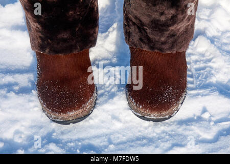 Big brown winter boots for women with a natural fur on the snow Stock Photo