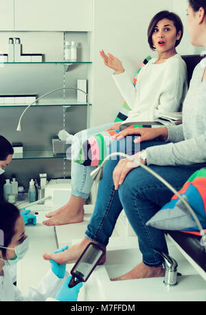 Pair of happy french  women clients getting pedicure in modern nail salon Stock Photo