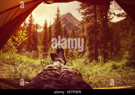 View from inside a tent in the garden, focus on the legs. The evening sun tinting Stock Photo