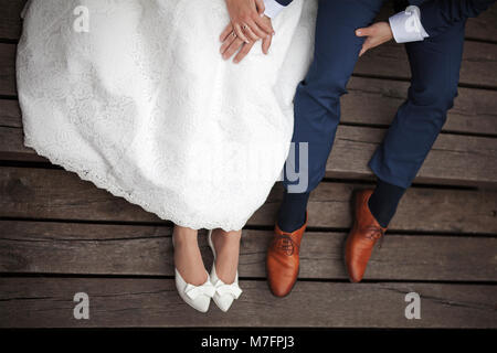 Wedding couple sitting on wooden pier. Stock Photo