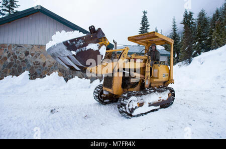 Clearing snow from around the house with a Cat 931 loader. in Sanders County, Montana Stock Photo