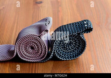 two men's ties, rolled up on a wooden background Stock Photo