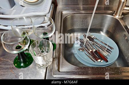 Dirty plates and cutlery in kitchen sink before washing Stock Photo