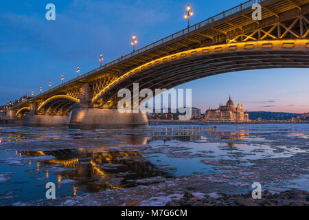 A span of the Margaret Bridge in Budapest with ice floes on the Danube and Parliament in the background Stock Photo