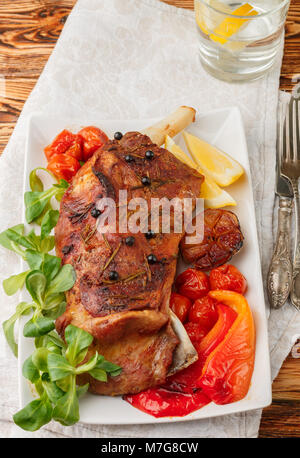 Lamb, baked in the oven with spices - rosemary, garlic and juniper. Tomatoes, peppers and herbs. The gourmet dinner. Selective focus Stock Photo