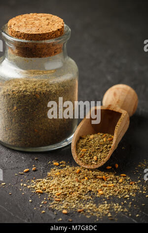 Zaatar - mix of Oriental spices on a dark stone background. Seasoning made from dried herbs, mixed with sesame seeds, sumac, salt and other spices. Se Stock Photo