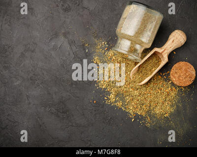 Zaatar - mix of Oriental spices on a dark stone background. Seasoning made from dried herbs, mixed with sesame seeds, sumac, salt and other spices. To Stock Photo