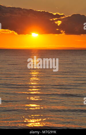 Sunset with sun peeking through cloud over freshwater Lake Superior in northern Wisconsin, USA Stock Photo