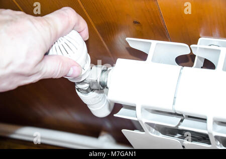 Hand regulates temperature in radiator Stock Photo