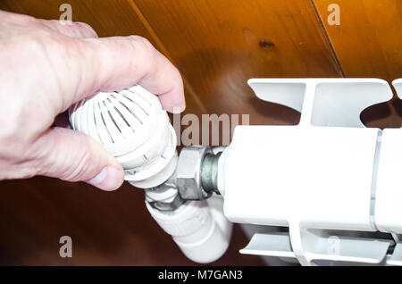 Hand regulates temperature in radiator Stock Photo