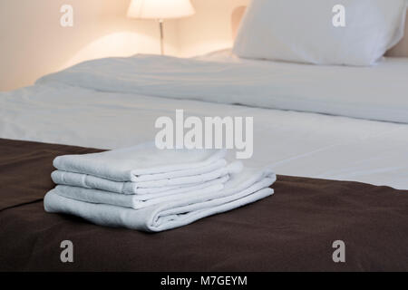 Freshly laundered fluffy towels on bed in hotel Horizontal Stock Photo