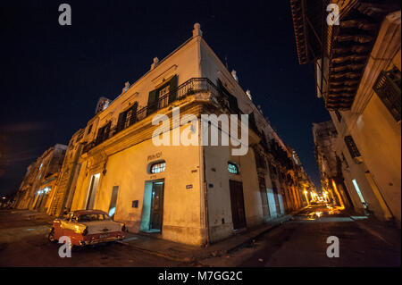 A classic American car parked outside a pharmacy in Havana, Cuba, at night Stock Photo