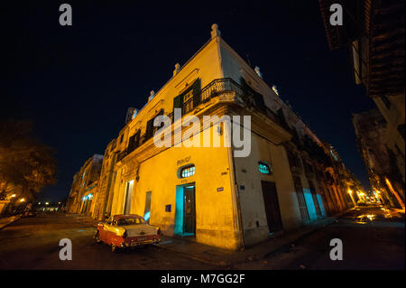 A classic American car parked outside a pharmacy in Havana, Cuba, at night Stock Photo