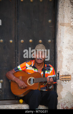 A colorfully dressed man plays the guitar and sings in Old Havana, Cuba Stock Photo