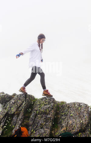 A cheerful tourist woman walking with pleasure walks the cliffs. The lifestyle of summer vacations by nature, the concept of adventure hiking and trav Stock Photo
