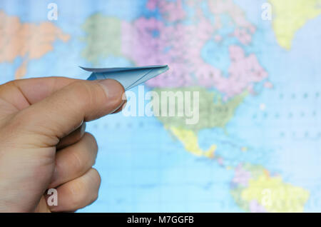 photo of man's hand holding toy paper airplane against map of the world. image is retro filtered Stock Photo
