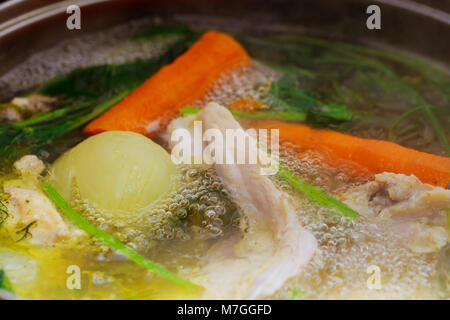 The soup is cooked in a large pot in the kitchen in the restaurant. cook chicken broth Stock Photo