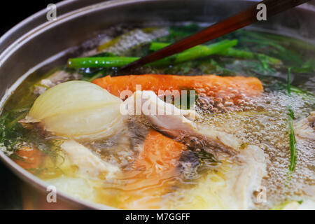 cook chicken broth Adding chicken wings into saucepan. Cooking chicken broth. Stock Photo