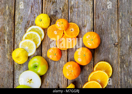 sliced citrus mix lemon grapefruit lime and orange in geometrical shapes on dark wood rustic background soft focus overhead-angle shot Stock Photo