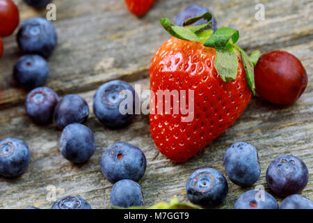 summer fruits on a wooden table. Blueberries Grape Strawberries Organic Healthy Products Stock Photo