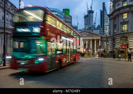 Red London bus on Bank junction at night with green traffic light illuminating front Stock Photo