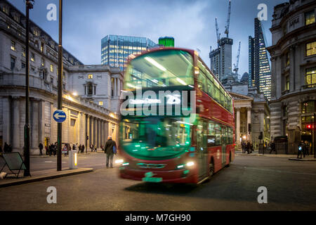 Red London bus on Bank junction at night with green traffic light illuminating front Stock Photo