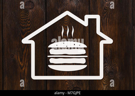 Paper house with burger inside on wooden background, fastfood concept. Abstract food conceptual image Stock Photo