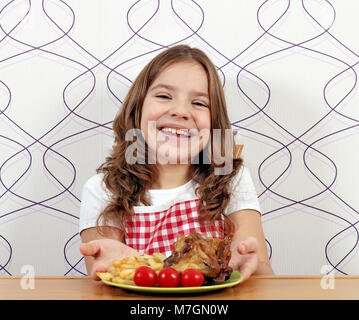 happy little girl with roasted chicken wings on plate Stock Photo