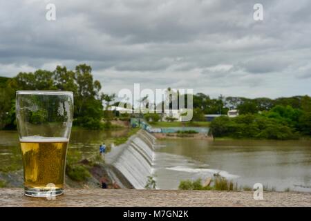 Drinking a beer with views of water overflowing the weir after recent heavy rain, Riverview Tavern in Douglas Townsville Queensland Australia Stock Photo