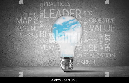 Glass lightbulb with skyscape inside with business related terms on dark grey wall on background. 3D rendering. Stock Photo