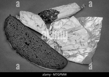Breakfast theme still life. Bread, Roquefort cheese and smoked sausage on craft paper background. Black and white photo Stock Photo