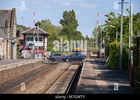 A Northern Rail pacer train departs  Parbold  (Lancashire) as the level crossing re opens to road traffic with cars crossing Stock Photo