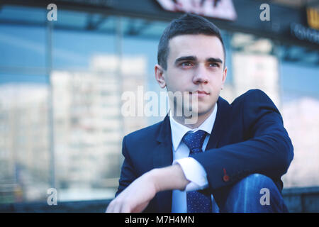 young businessman sitting on the steps of the office Stock Photo