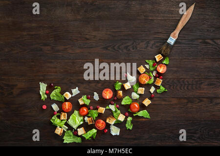 Yummy top view composition of fresh healthy salad ingredients artistically arranged on dark wooden table. Traditional Caesar salad components: lettuce Stock Photo