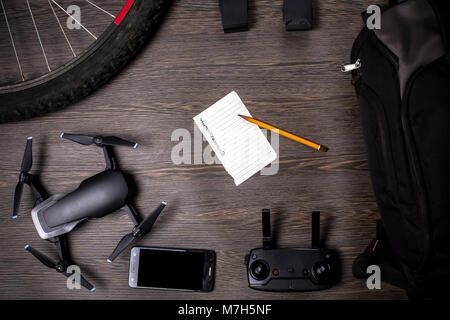 drone and bicycle wheel, near a backpack and battery, with a leaf for planning, on a woody background, concept of portable quadrocopter Stock Photo