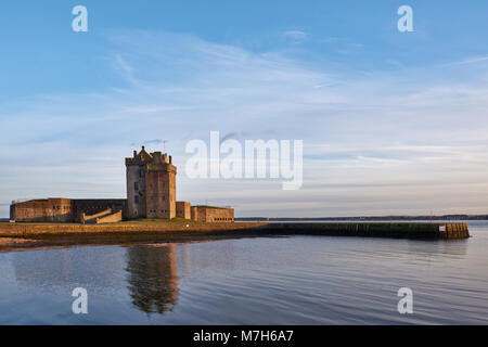 The Setting sun from the Tay Estuary reflects off the Fortified walls of Broughty Castle, near Dundee in Angus, Scotland. Stock Photo