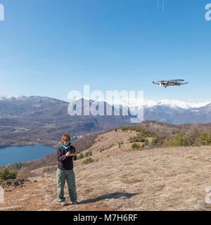 Turin, Italy - March 8, 2018: woman flying drone outdoors with remote control in Turin countryside, Italy. One person in scenic landscape driving dron Stock Photo