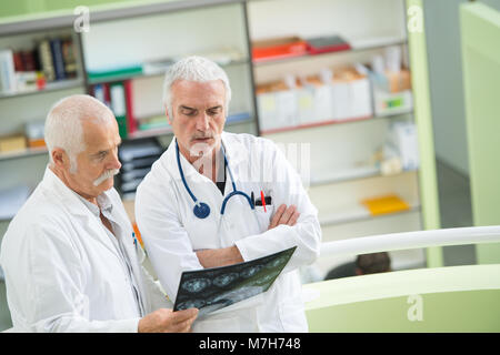 two experienced doctors looking at two x-ray images Stock Photo