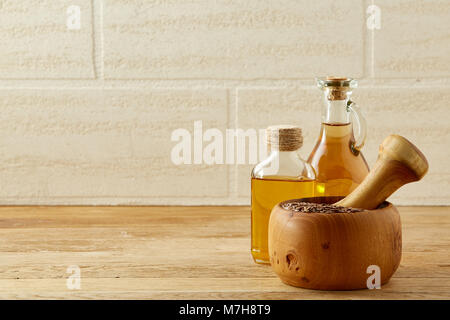 Picturesque composition of oil jars, pestle and mortar with motley grass over wooden background, selective focus. Nutrition and nourishment for your b Stock Photo