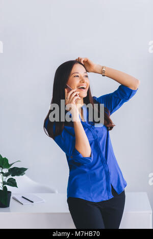 Attractive latin modern lady emotionally talking on the phone and laughing . Interactive conversation Stock Photo
