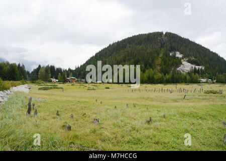 The Canada-US boundary line running up a forested hilltop separating the towns of Hyder, Alaska (below) and Stewart, British Columbia. Stock Photo