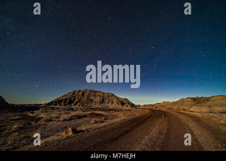 A moonlit nightscape of the badlands loop road in Dinosaur Provincial Park. Stock Photo