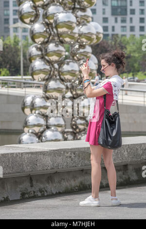 Young lady taking a selfie outside the Silver Balls sculpture of the Guggenheim Musuem, Bilbao, Vizcaya, Pais Vasco, Spain, Stock Photo