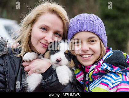 Mother hugging daughter with peppy Stock Photo