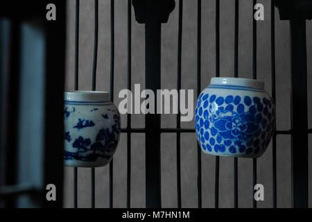 Vintage and old wooden bird cage with water cups from porcelain and Chinese paintings on it Stock Photo