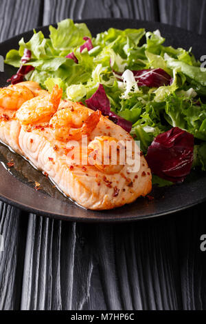 Grilled salmon with shrimps and lettuce on a plate close-up on the table. vertical Stock Photo