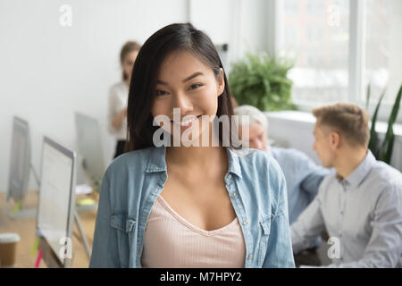 Smiling asian office employee looking at camera working with col