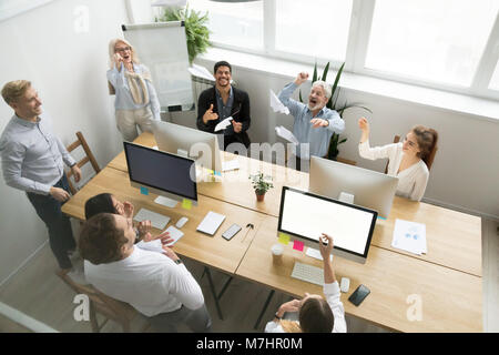 Diverse happy office team launching paper planes together, top v Stock Photo